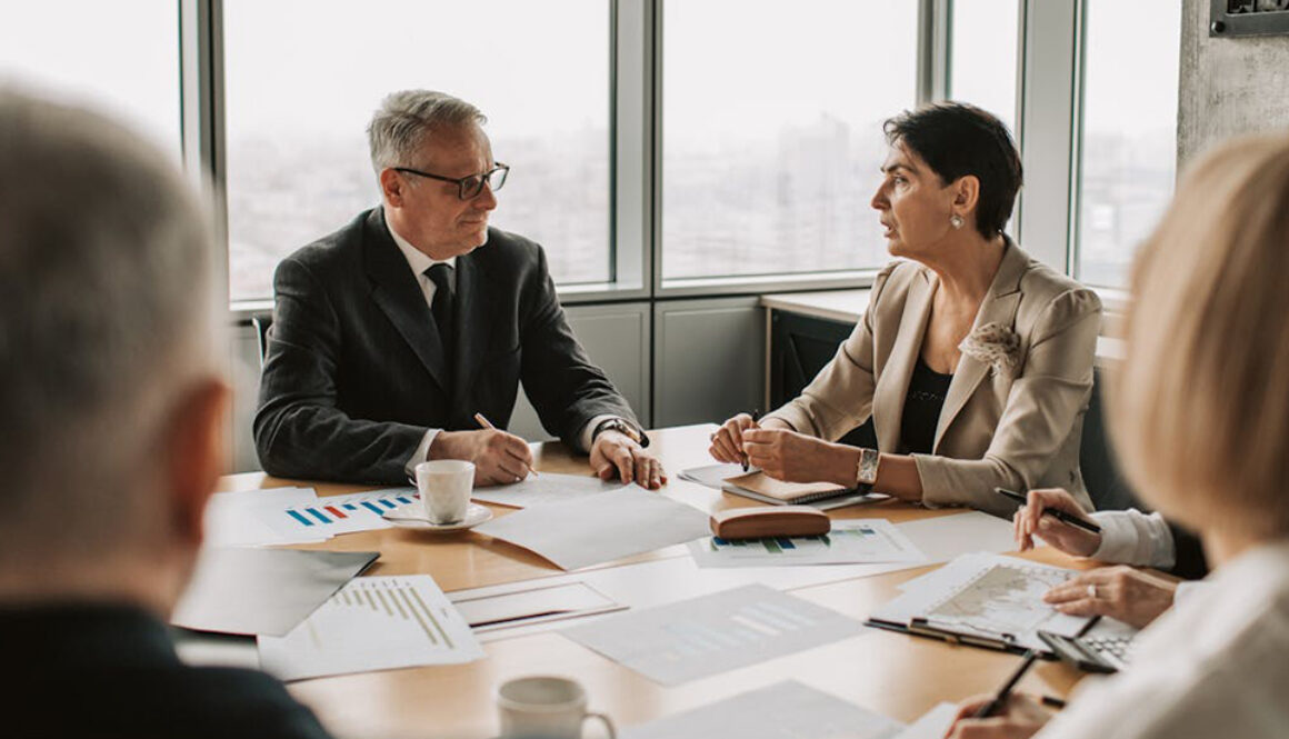 People, sitting around a table, conducting a meeting in Business English