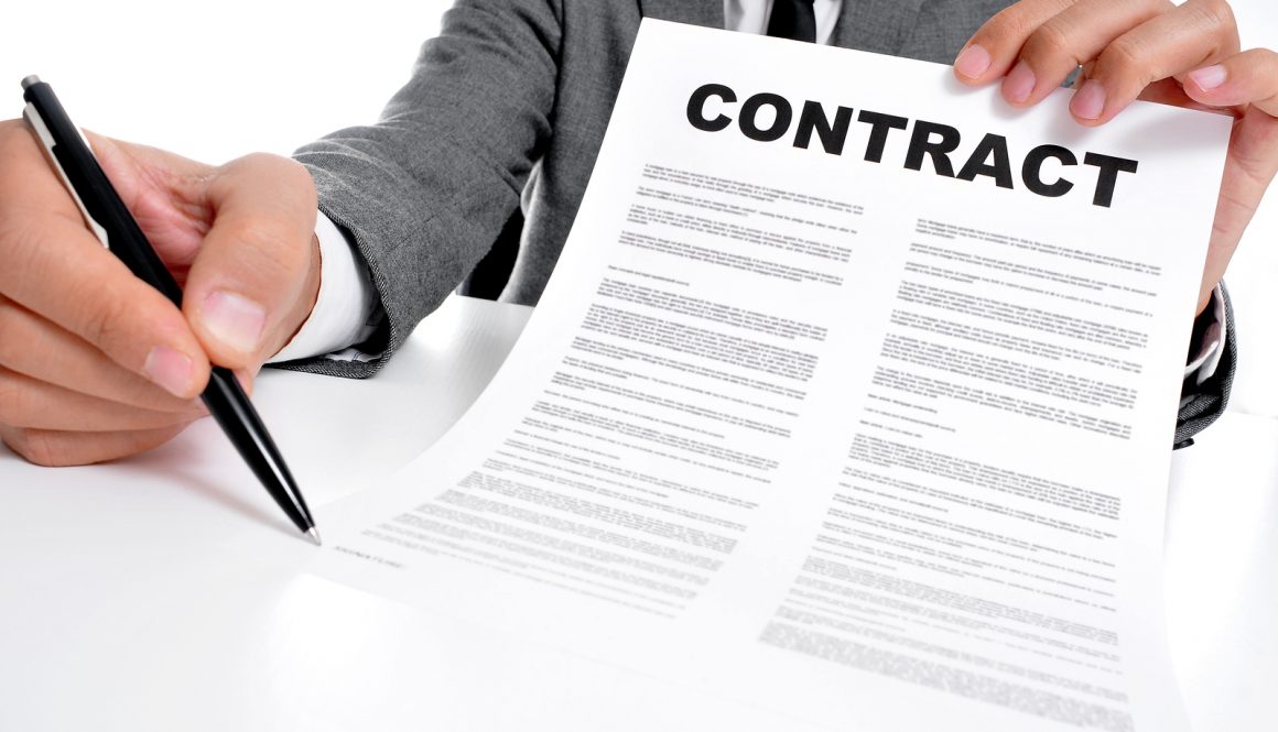 man wearing a suit sitting in a table showing a contract and whe