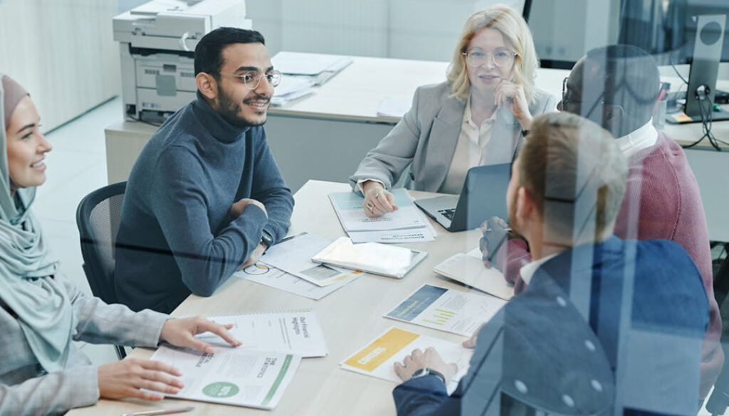 International group of office workers in a team meeting around a table. Euro English