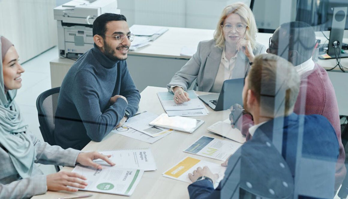 International group of office workers in a team meeting around a table. Euro English