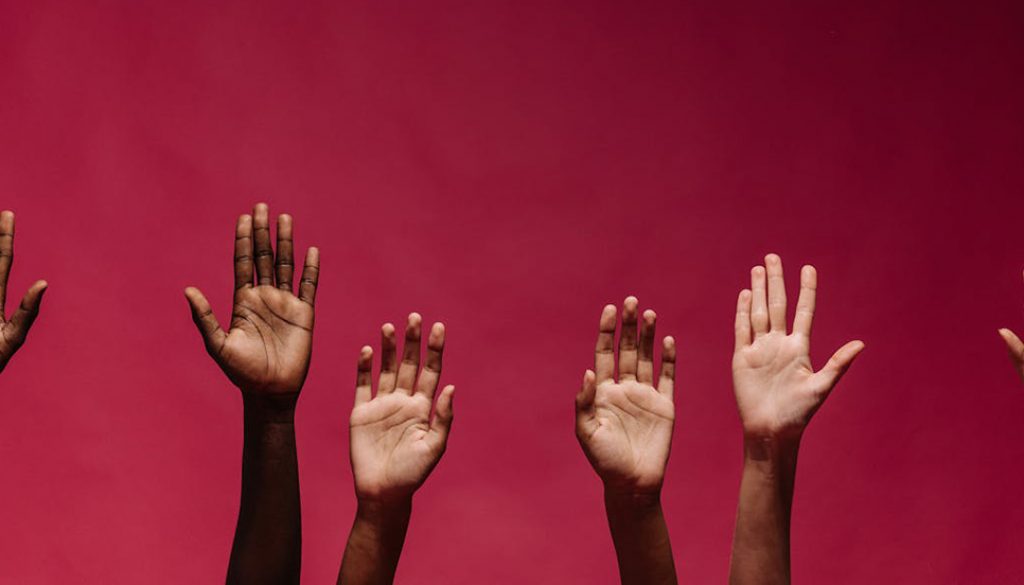 Six raised, multi-ethnic hands, representing a language family.