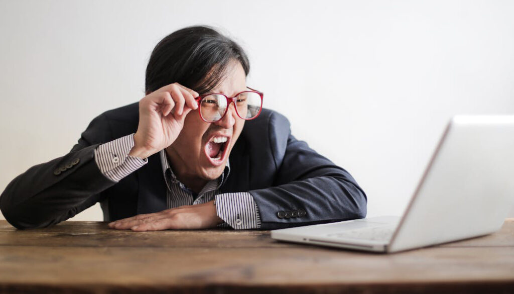 Young, Asian man yelling at a cimputer, as he tries and fails to get good multilingual customer support.