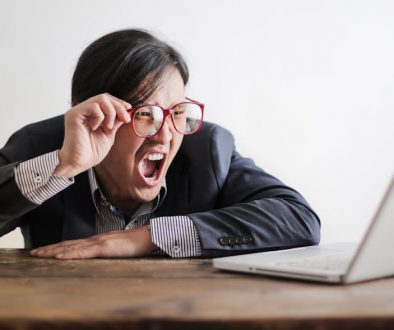 Young, Asian man yelling at a cimputer, as he tries and fails to get good multilingual customer support.